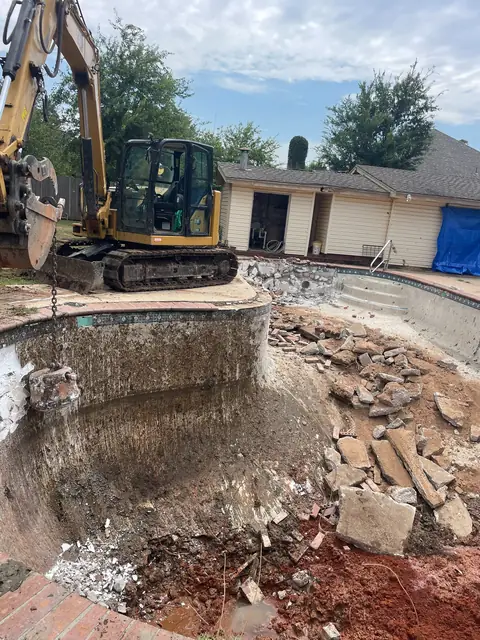 Excavator breaking out a pool shell